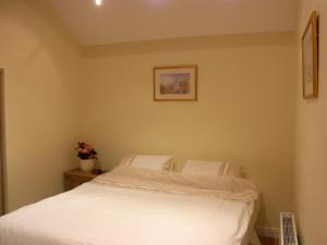 LaxeyPinfold Holiday Cottage的卧室配有白色的床,墙上挂着一幅画