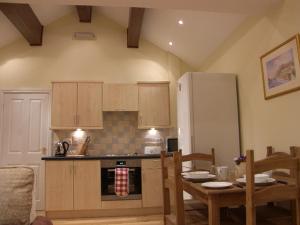 LaxeyPinfold Holiday Cottage的厨房配有桌椅和冰箱。