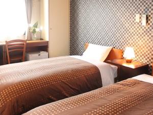羽村市HOTEL LiVEMAX BUDGET Tokyo Hamura Ekimae的一间卧室配有两张床和一张带台灯的桌子