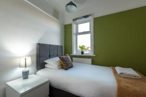 南安普敦Comfortable and convenient stay 3 bed house的绿色卧室设有白色的床和窗户
