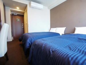 横滨HOTEL LiVEMAX Yokohama Motomachi Ekimae的两张位于酒店客房的床,配有蓝色床单