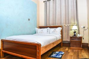 NyahururuBreeze Hotel Nyahururu的一间卧室设有一张床和蓝色的墙壁