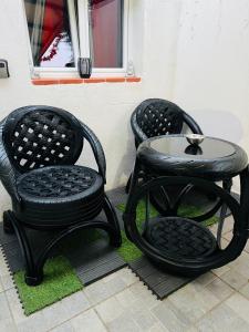 维特罗勒Douceur d’une nuit (studio avec jaccuzi privatif)的天井上配有2把黑色椅子和1张桌子