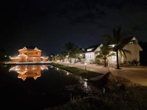 Ban Mae ChoMonMin Farmstay的夜晚在池塘里反射的房屋