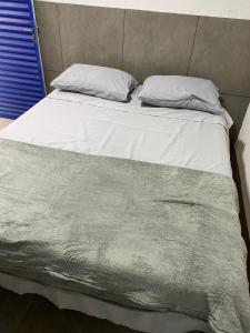 戈亚尼亚GYN SUITES - SUITES EM GOIÂNIA GO的一张带白色床单和枕头的床