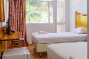 沙布拉Hotel NAVI的客房设有两张床、一张桌子和一个窗户。
