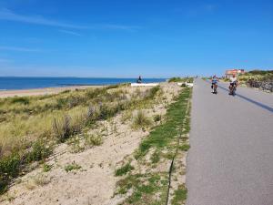 卡德赞德Le Normandy 5star的一群人骑着自行车沿着海滩旁的道路行驶