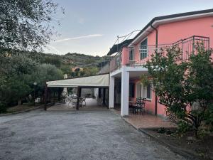 因佩里亚Agriturismo Le Mimose的粉红色的建筑,前面有帐篷