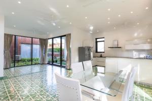 果阿旧城Luxury 3BHK Villa with Private Pool near Anjuna的厨房以及带玻璃桌和白色椅子的用餐室。