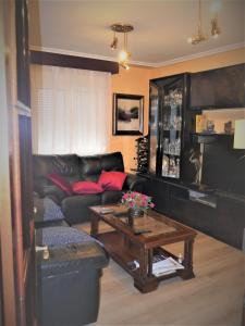 阿维莱斯Habitaciones en Aviles的客厅配有黑色真皮沙发和咖啡桌