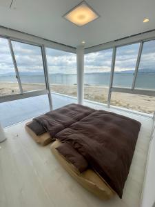 福冈Luxury Villa Saitozaki UMIHOTARU的海滩前的卧室配有一张大床