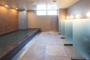 泉佐野关西机场阿斯顿广场酒店的一间设有摊位和地板的公共浴室
