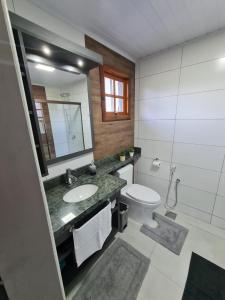 格拉玛多Aconchego Ipê Amarelo的一间带水槽、卫生间和镜子的浴室