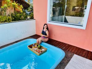 帕拉蒂Casa Premium Paraty com Piscina - Passeio de Escuna de Cortesia incluso的坐在游泳池旁阳台的女人