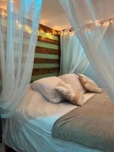 洛翁普拉日ESCAPE ZEN Oasis tropicale & Spa privatif的一张带白色窗帘和枕头的床