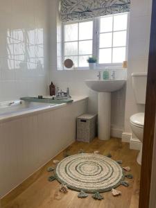 布罗德韦Lotties Cottage的浴室设有盥洗池和地板上的地毯。