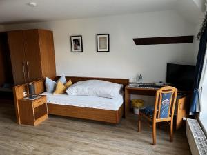 Pension Zur Mühle的一间卧室配有一张床、一张书桌和一台电视