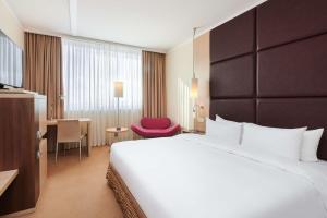 什切青丽笙布鲁什切青酒店的酒店客房设有一张大床和一张红色椅子。