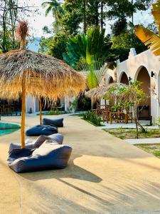拉迈Zibá Home Suites的一个带草伞和游泳池的度假胜地