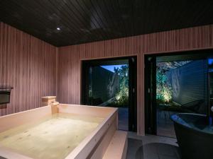 宫岛Bettei Fujiya的一个带滑动玻璃门的按摩浴缸