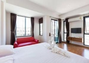 卡马拉海滩Buk Inn Hotel SHA Plus的卧室配有一张白色大床和红色椅子