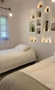 塔里哈La Casa de la Huerta的配有2张床的白色墙壁和架子