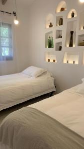 塔里哈La Casa de la Huerta的配有2张床的白色墙壁和架子
