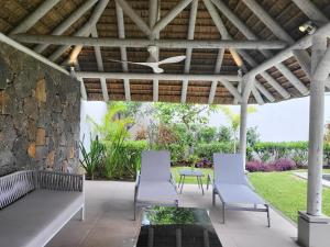 格兰贝伊Villa de Luxe à Grand Baie avec piscine V12的庭院设有白色椅子和石墙