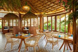 Nong SaraiLA COCOTTE VILLA & FARM KHAO YAI的餐厅设有木桌、椅子和窗户。