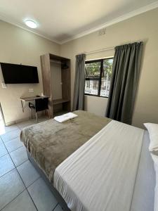 约翰内斯堡Ecomotel Louis Botha的一间卧室配有一张大床、一张桌子和一个窗户。