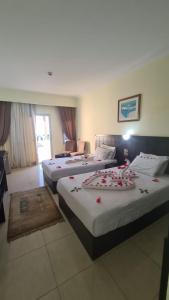 沙姆沙伊赫Uni sharm aqua park的酒店客房,配有三张带鲜花的床