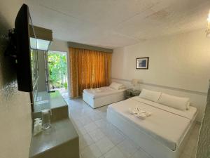 长滩岛卡萨皮拉尔海滩度假酒店的一间带两张床和电视的客厅