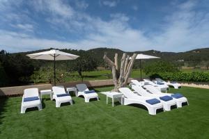 伊维萨镇Villa Simona Ibiza的一群白色的椅子和遮阳伞在草地上