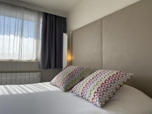 瓦朗斯钟楼瓦伦斯南酒店的一间卧室配有一张带两个枕头的床