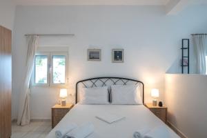 普拉基亚斯Vrisidia Cottage - Nature, Seaview & Relax的一间卧室配有白色的床、两张桌子和两个窗户