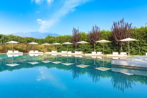 加里Ramo d'Aria Etna Boutique Hotel的一个带遮阳伞和椅子的游泳池以及一个游泳池