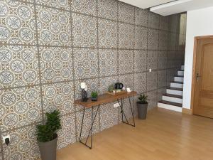 普拉亚KAZARÃO DI MAVETE - Guesthouse的一间设有瓷砖墙、桌子和植物的客房