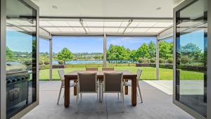 陶朗加The Lakehouse - Tauranga Holiday Home的一间带桌椅和大窗户的用餐室