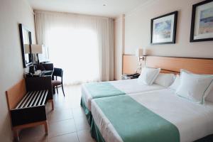 拉曼加戴尔马尔梅纳Poseidon La Manga Hotel & Spa - Designed for Adults的酒店客房带一张大床和一把椅子