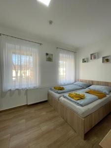 琼格拉德Dóra Vendégház的卧室设有两张床,拥有白色的墙壁和木地板