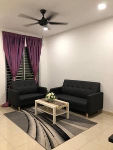 雪邦MOFA Homestay Near KLIA Airport的客厅配有2张黑色沙发和咖啡桌