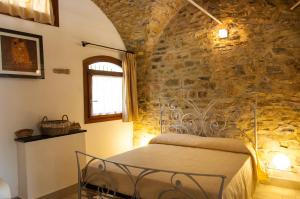 因佩里亚Appartamenti Antico Frantoio Doria的卧室配有一张石墙床