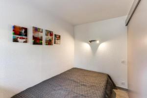 圣普里安海滩Saint-Cyprien Plage的一间卧室配有一张床,墙上挂着一些图片