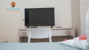 苏莎亚CoralK Apartments Sosúa的一张桌子上的电视机,上面有白色的椅子