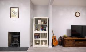 巴斯Bath City Skyline Spacious 3 Bed House for family的客厅配有带吉他手架的白色书架