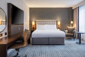 伦敦伦敦切尔西希尔顿逸林酒店的酒店客房配有一张床、一张书桌和一台电视。