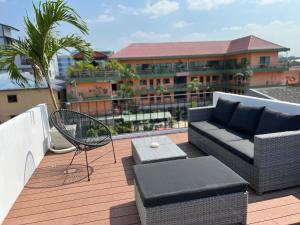 芭堤雅市中心ONE LODGE Pattaya的阳台配有沙发、椅子和桌子
