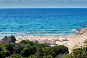奇亚Conrad Chia Laguna Sardinia的海滩上设有白色的遮阳伞和海洋