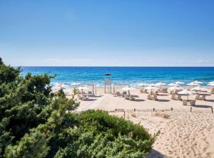 奇亚Conrad Chia Laguna Sardinia的海滩上设有遮阳伞和椅子,还有大海