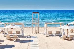 奇亚Conrad Chia Laguna Sardinia的海滩上的一组椅子和遮阳伞